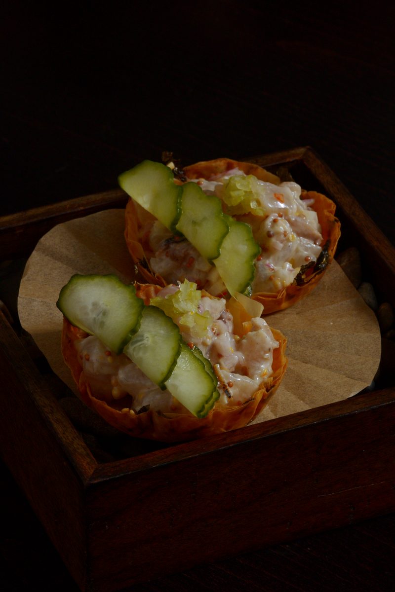 Two cups of Sinuglaw ceviche topped with sliced cucumber, served in a small wooden box at Nanam in Takapuna